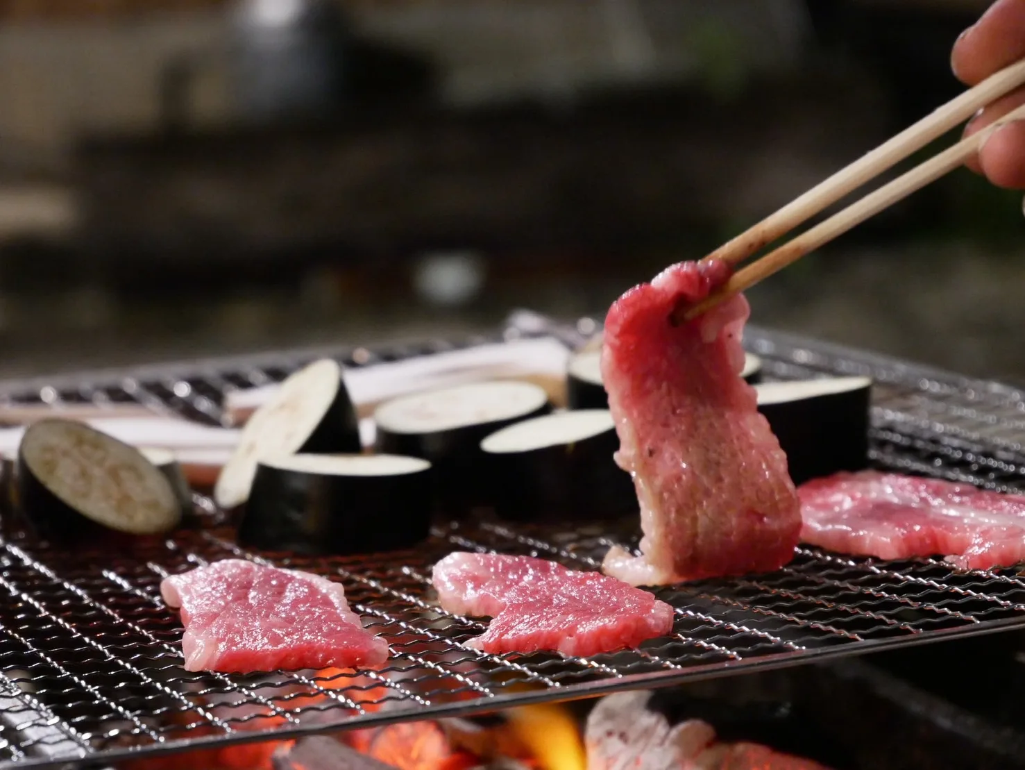炭火BBQの網で焼く肉と茄子、火の光