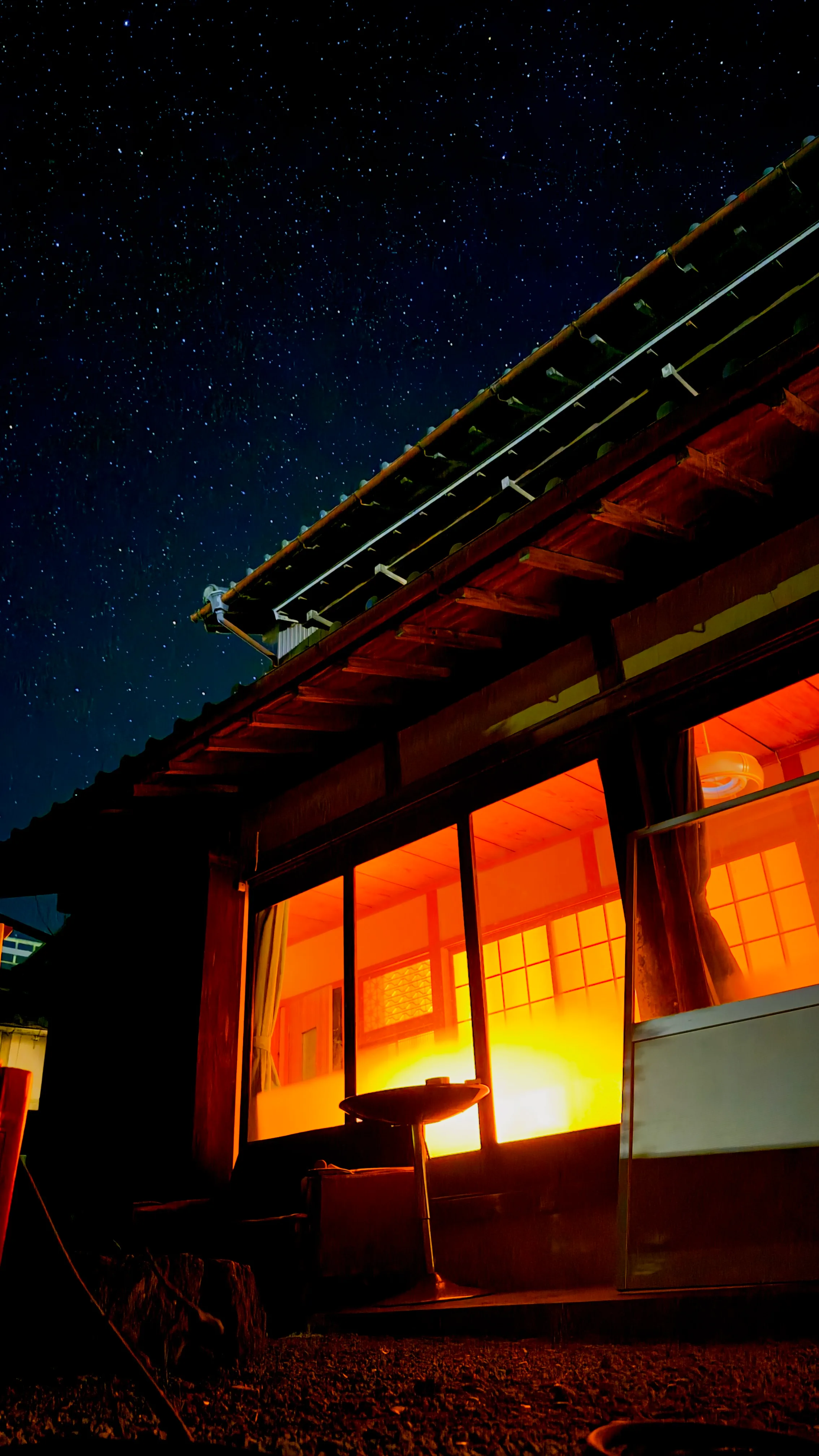 満天の星空と母屋の軒下、焚き火台のシルエット